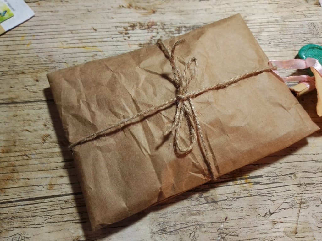 Colis emballe en papier kraft ficele, vu de dessus sur fond bois