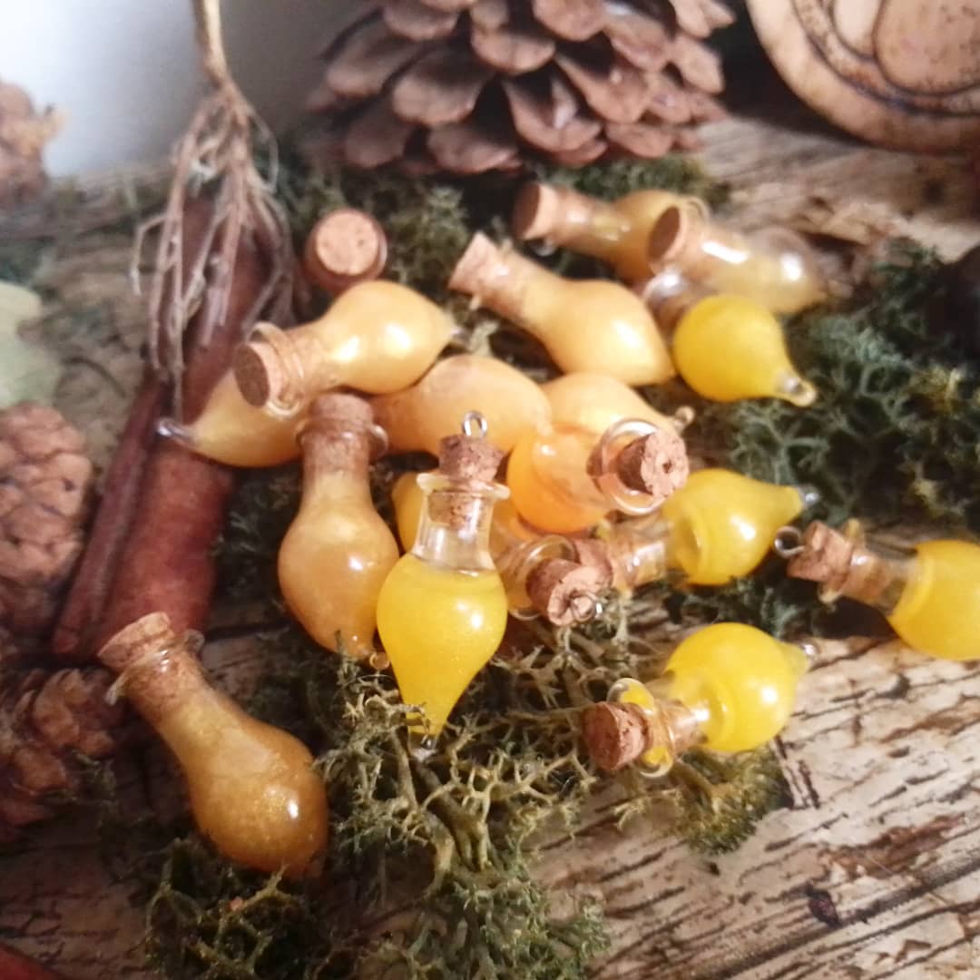 Pendentifs fioles de potion en verre ambre et bouchon liege, poses sur de la mousse