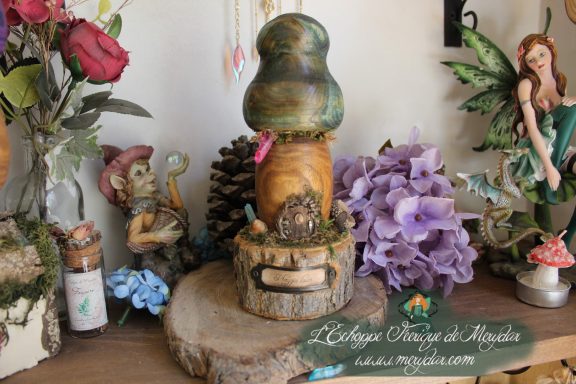 Figurine champignon vert fonce sur socle en bois, entouree de gnomes et de roses
