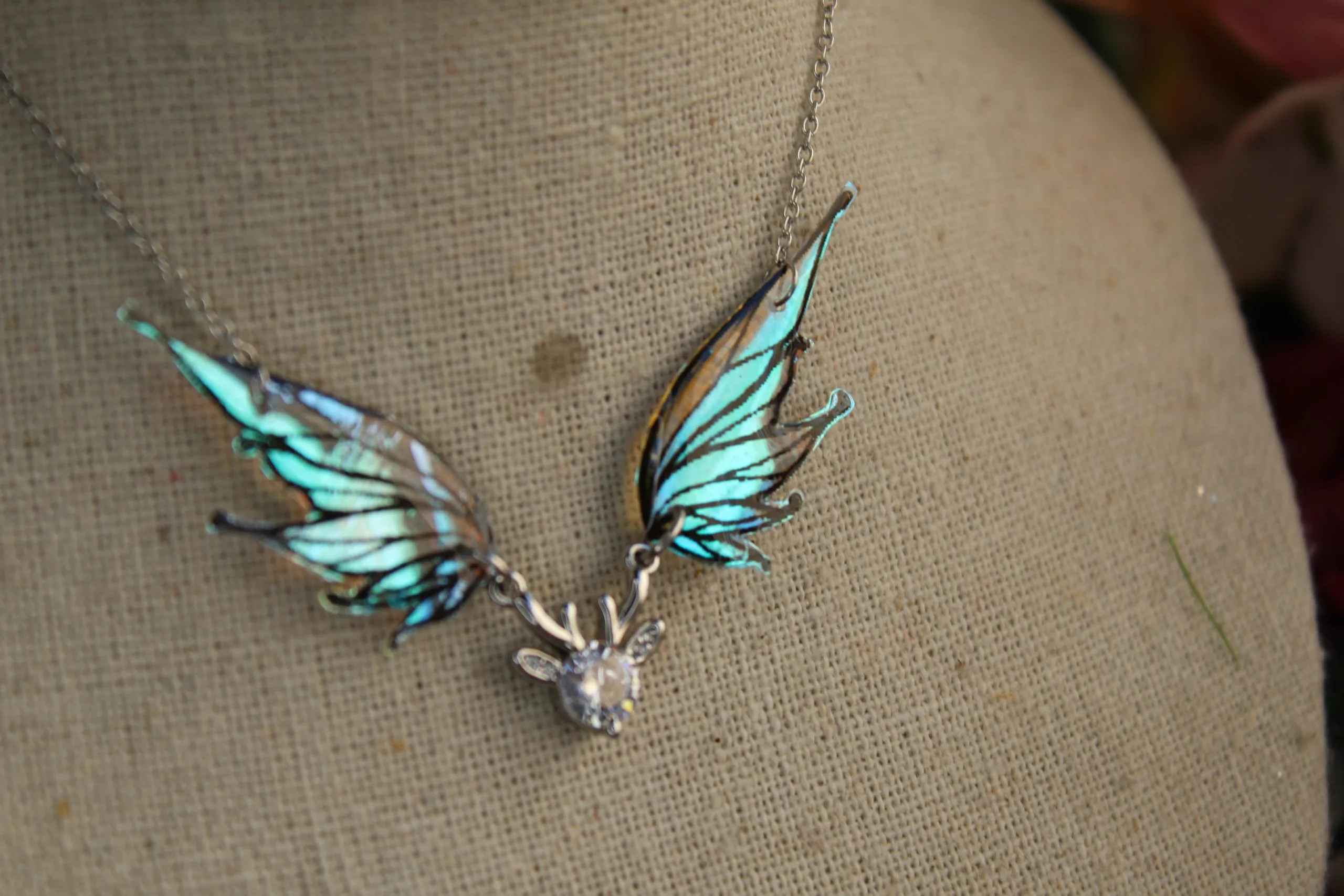 Pendentif féerique avec un petit renne entouré de deux ailes de fée déployées