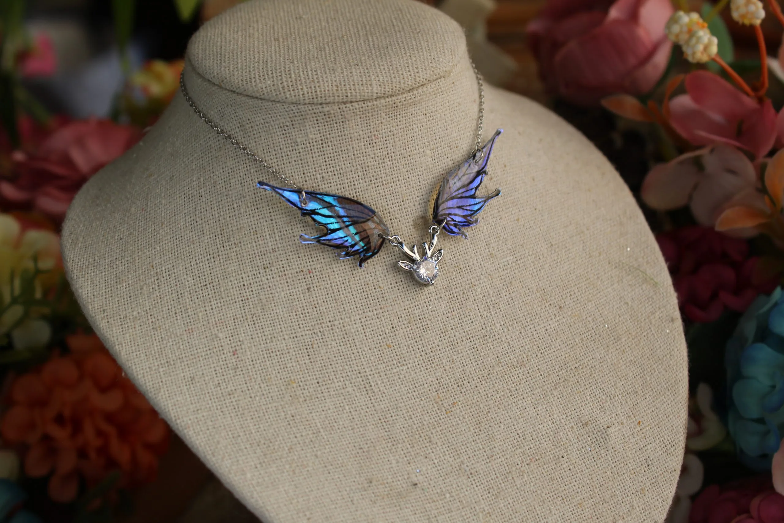 Pendentif féerique avec un petit renne entouré de deux ailes de fée déployées