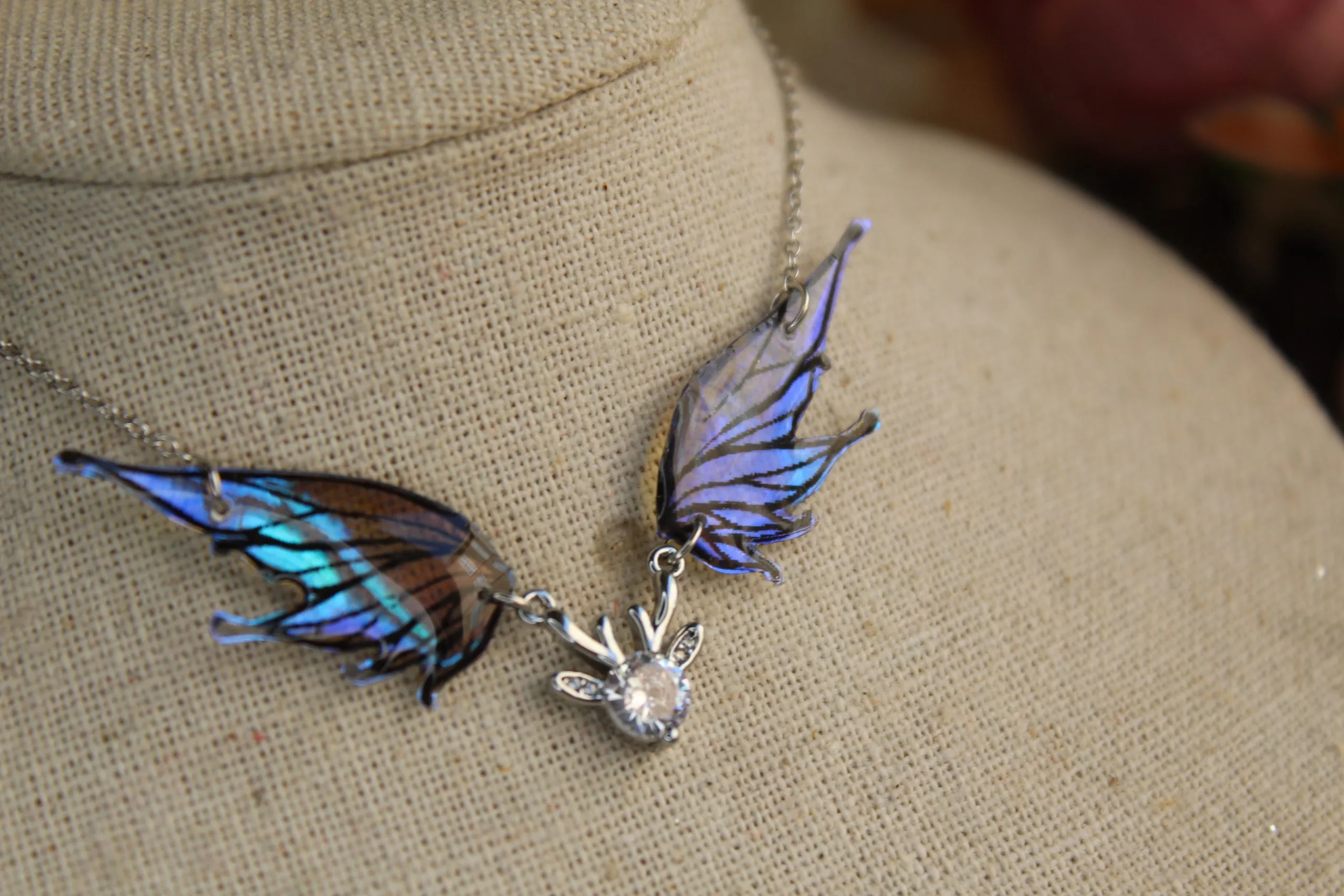 Pendentif féerique avec un petit renne entouré de deux ailes de fée déployées