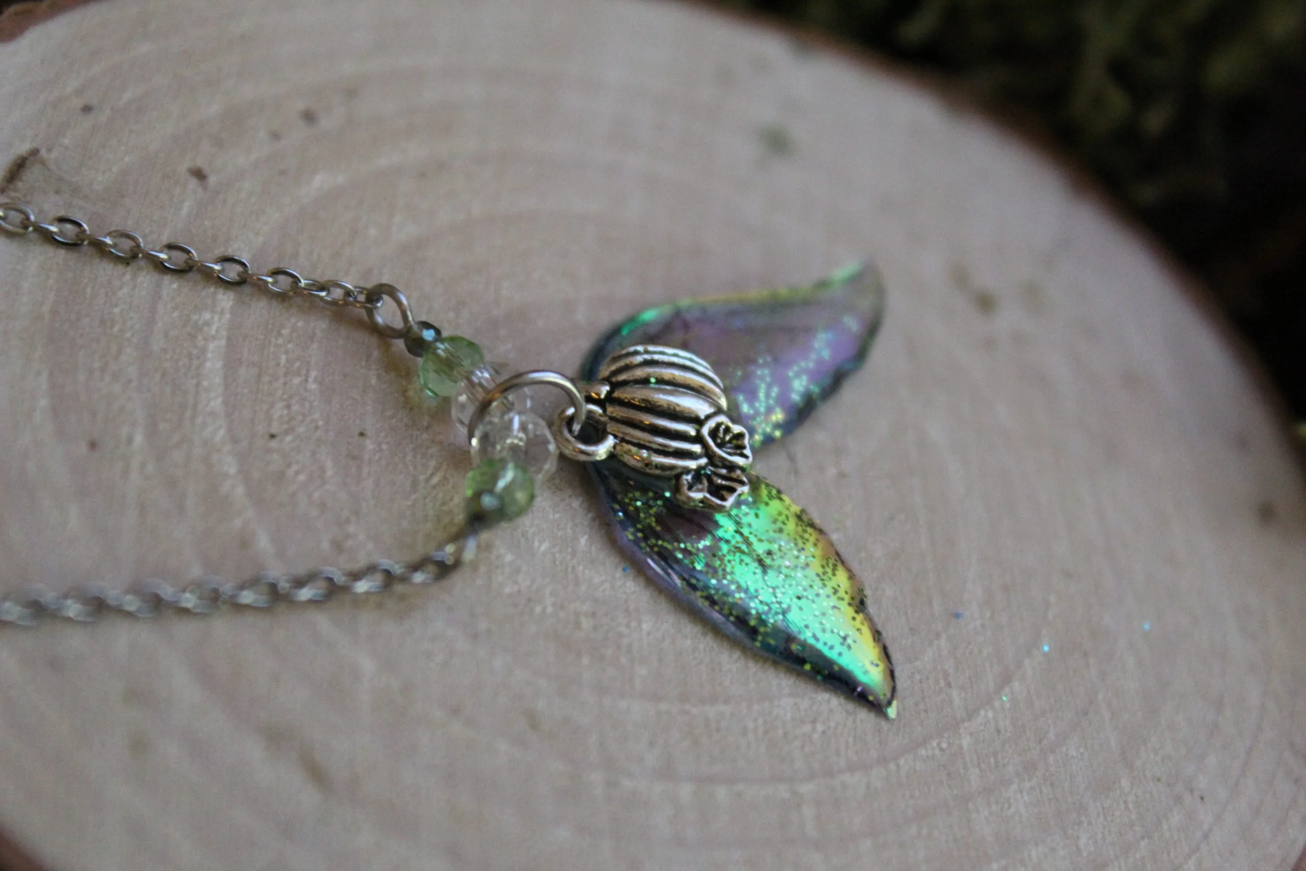 Pendentif féerique avec un petit renne entouré de deux ailes de fée déployées