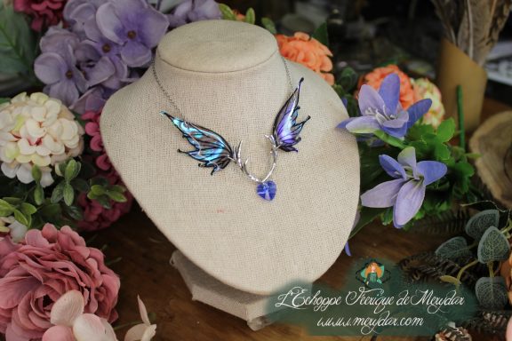 Collier double ailes de papillon violettes et bleues irisees avec pendentif cristal, sur buste fleuri