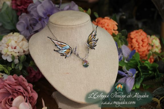 Collier double ailes de papillon ambrees et noires sur buste, fond floral