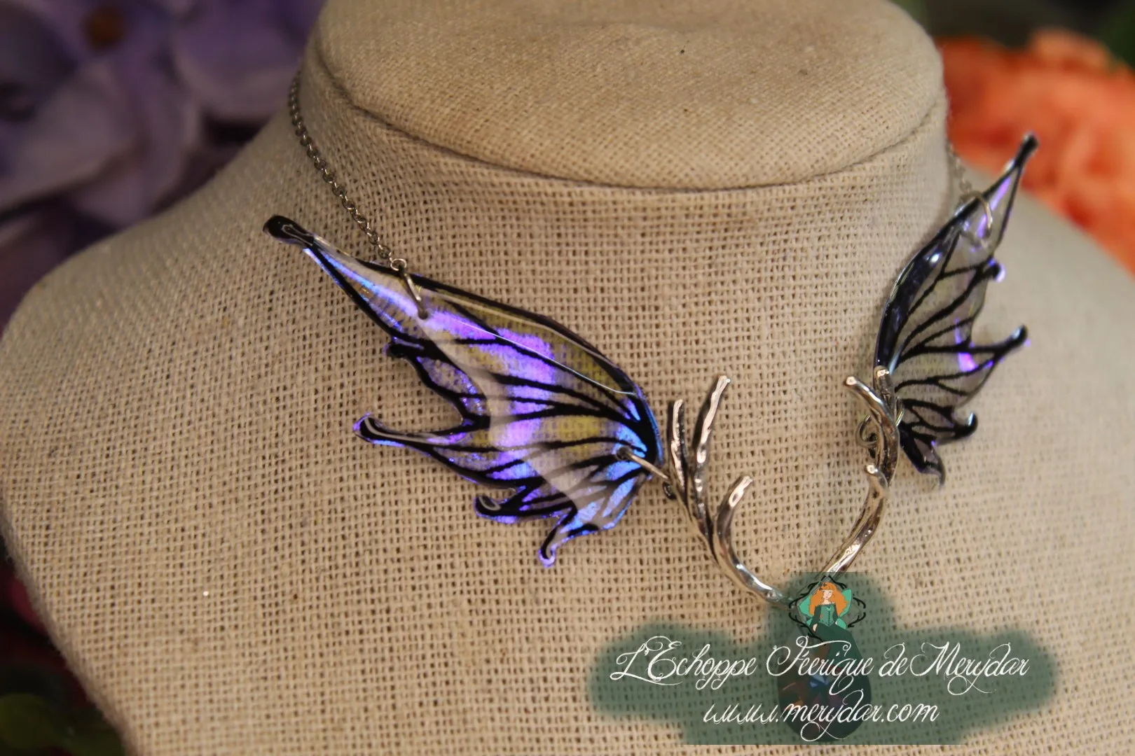 Collier double ailes de papillon violettes et bleues sur buste, fond floral