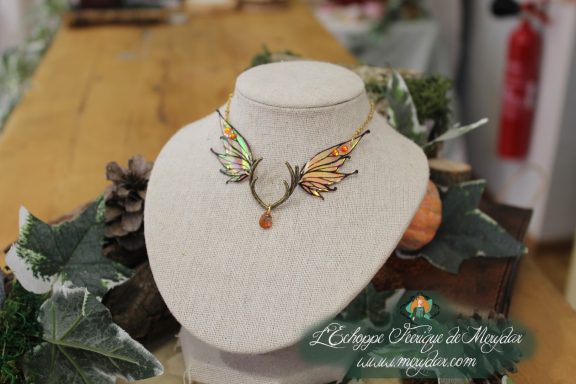 Collier ailes orange formant un pendentif en V avec gemme ambre, presente sur buste