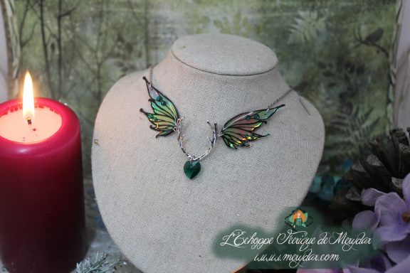 Collier double aile verte doree avec breloque coeur, pres d'une bougie