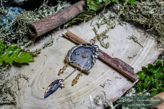 Pendentif medaillon rond en metal argente a motif texture, avec breloque feuille suspendue, sur mousse