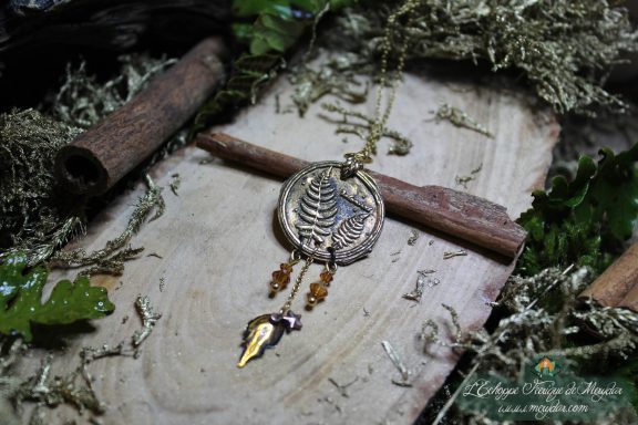 Pendentif medaillon rond en metal argente a motif texture, avec breloque goutte ambree suspendue