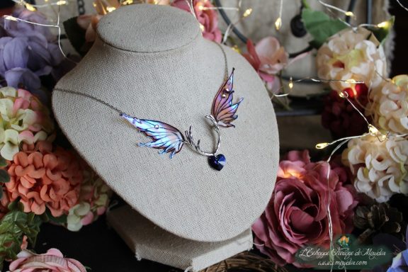 Collier double ailes de papillon roses et violettes sur buste, fond fleuri illumine