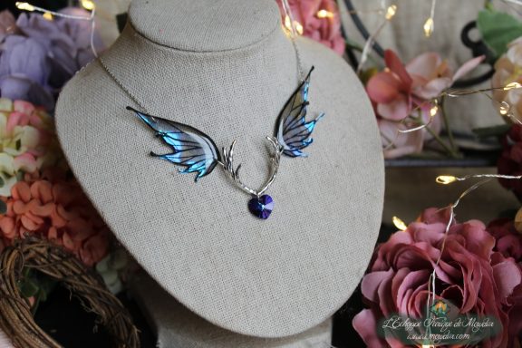 Collier double ailes de papillon bleu ciel avec bois de cerf central, sur buste fleuri illumine