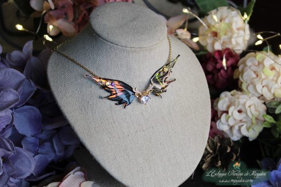 Collier aile de papillon bleue et violette avec petit pendentif clair, vue sur buste fleuri