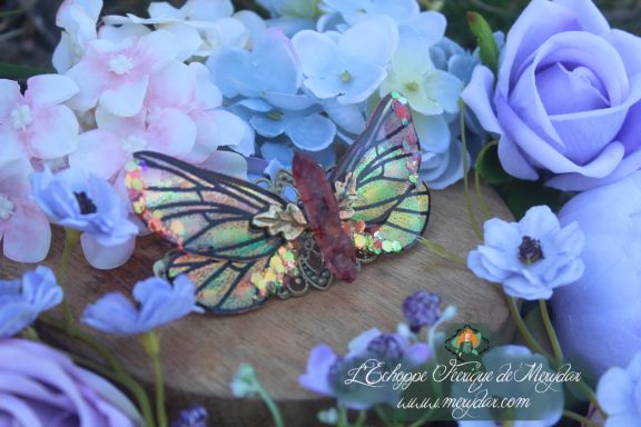 Barrette cheveux ailes de papillon rouge et dore, sur fond de fleurs