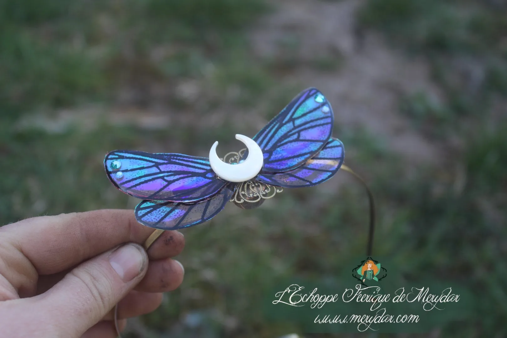 Serre-tete aile de papillon bleu violet tenu en main en exterieur