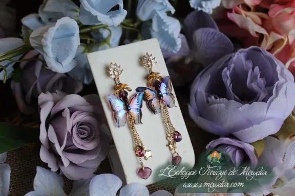 Boucles d'oreilles pendantes papillon bleu et dore avec chainettes, presentees sur carte