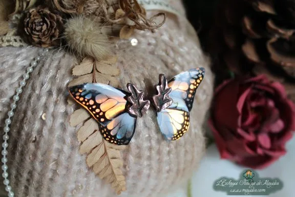 Barrette papillon monarque orange et noir, posee sur coussin de laine