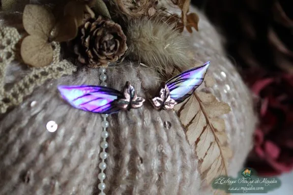 Paire d'epingles ailes violettes irisees, sur coussin de laine et fougere