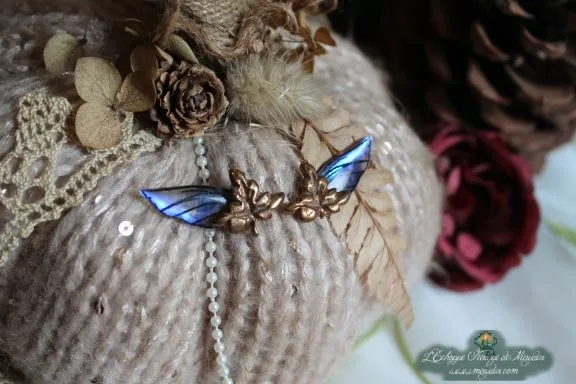 Paire d'epingles ailes bleues irisees, sur coussin de laine et fougere