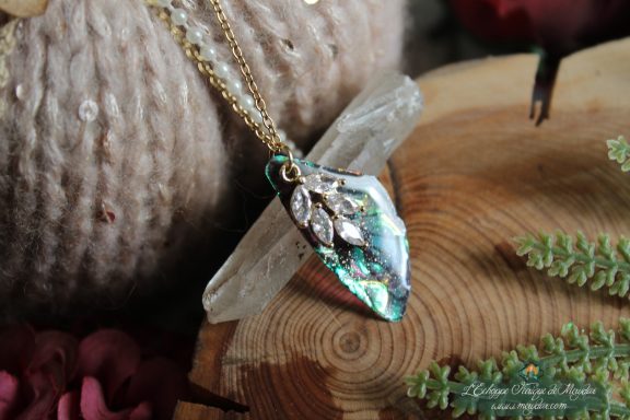 Pendentif aile unique turquoise verte avec breloque feuille, presente sur socle en bois