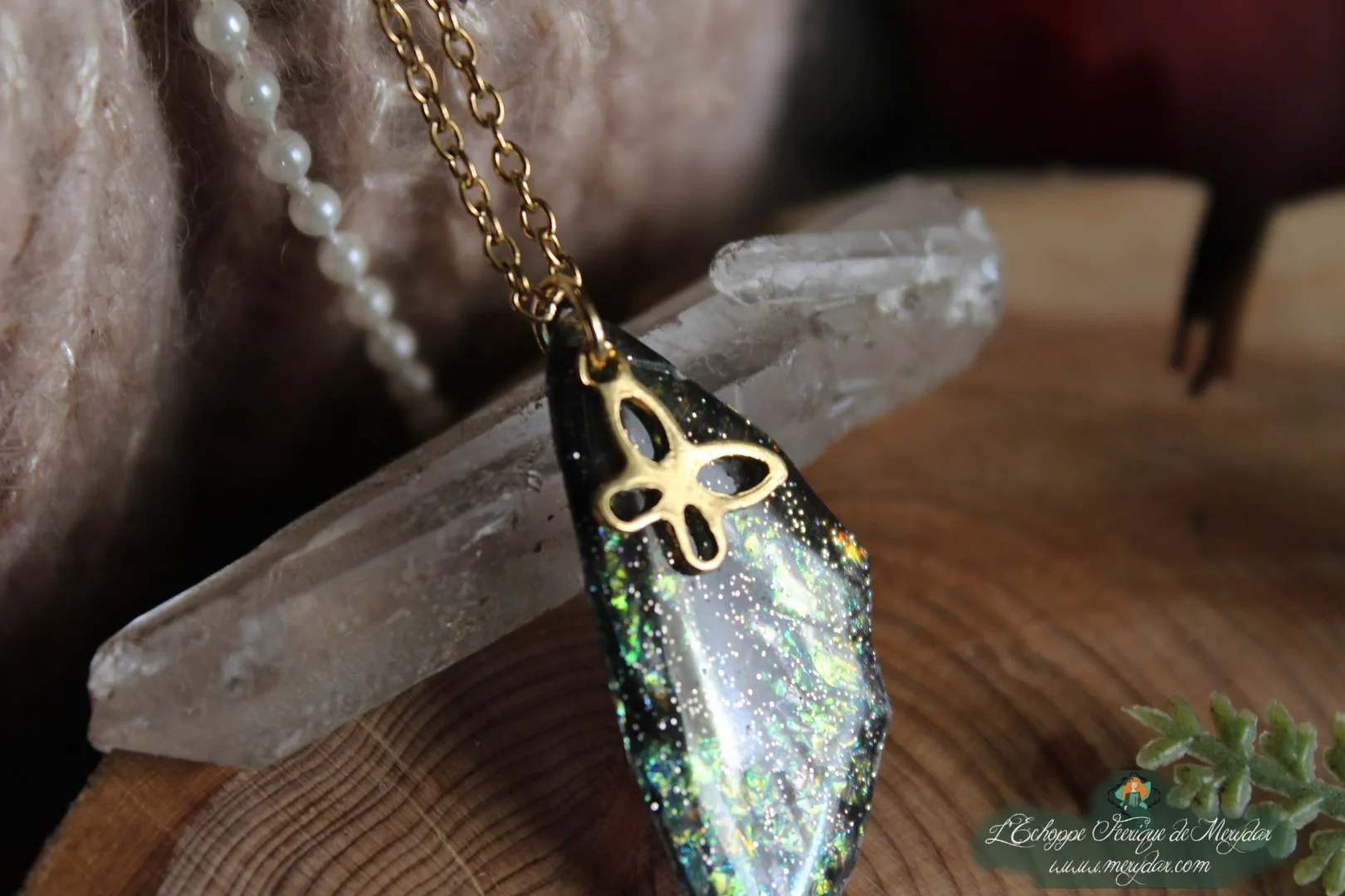 Pendentif aile unique noire et argentee avec breloque papillon, presente sur socle en bois
