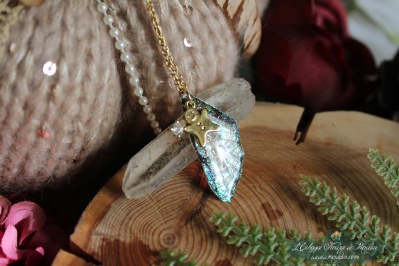 Pendentif aile unique turquoise verte avec breloque etoile, presente sur socle en bois