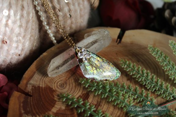 Pendentif aile unique blanche argentee avec breloque flocon, presente sur socle en bois