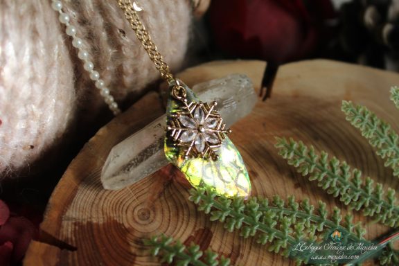 Pendentif aile unique doree verte avec breloque flocon, presente sur socle en bois