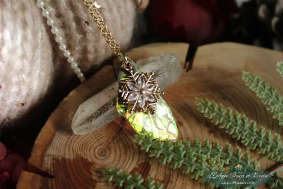Pendentif aile unique doree verte avec breloque flocon, presente sur socle en bois