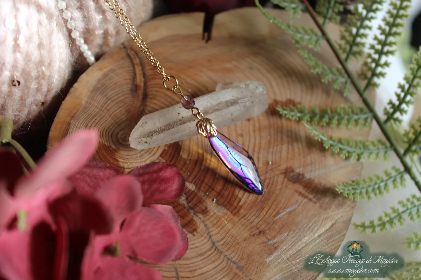 Pendentif fine aile violette avec perle pendante, presente sur socle en bois