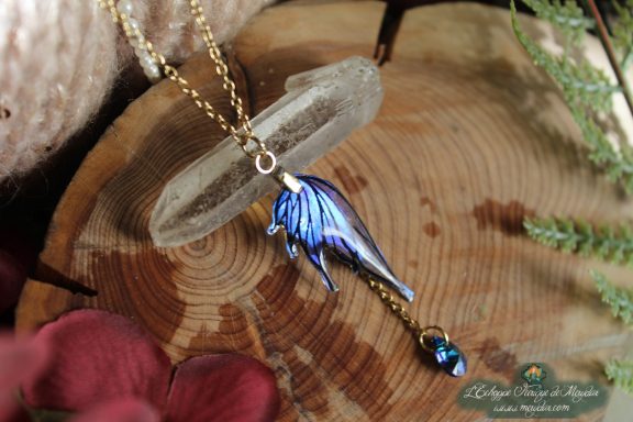 Pendentif aile bleue en forme d'aile d'ange avec perle bleue, presente sur socle en bois