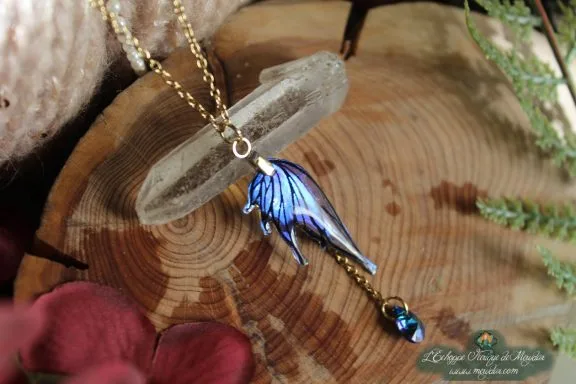 Pendentif aile bleue en forme d'aile d'ange avec perle bleue, presente sur socle en bois