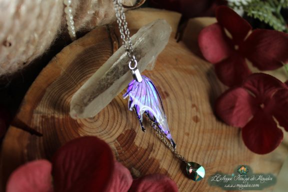 Pendentif aile de dragon violette avec perle pendante, presente sur socle en bois