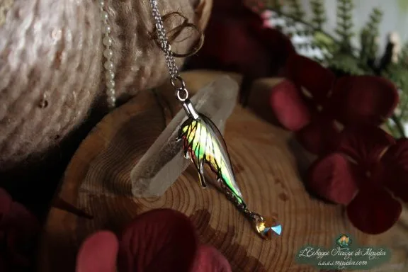 Pendentif aile de dragon verte doree avec perle pendante, presente sur socle en bois variante