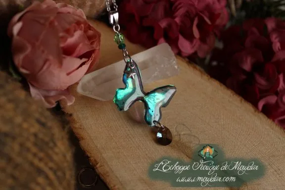 Collier pendentif papillon turquoise entier avec perle brune, presente sur socle en bois fleuri