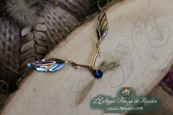 Bracelet chaine branche doree avec petite aile feuille bleue violette et perle bleue, gros plan