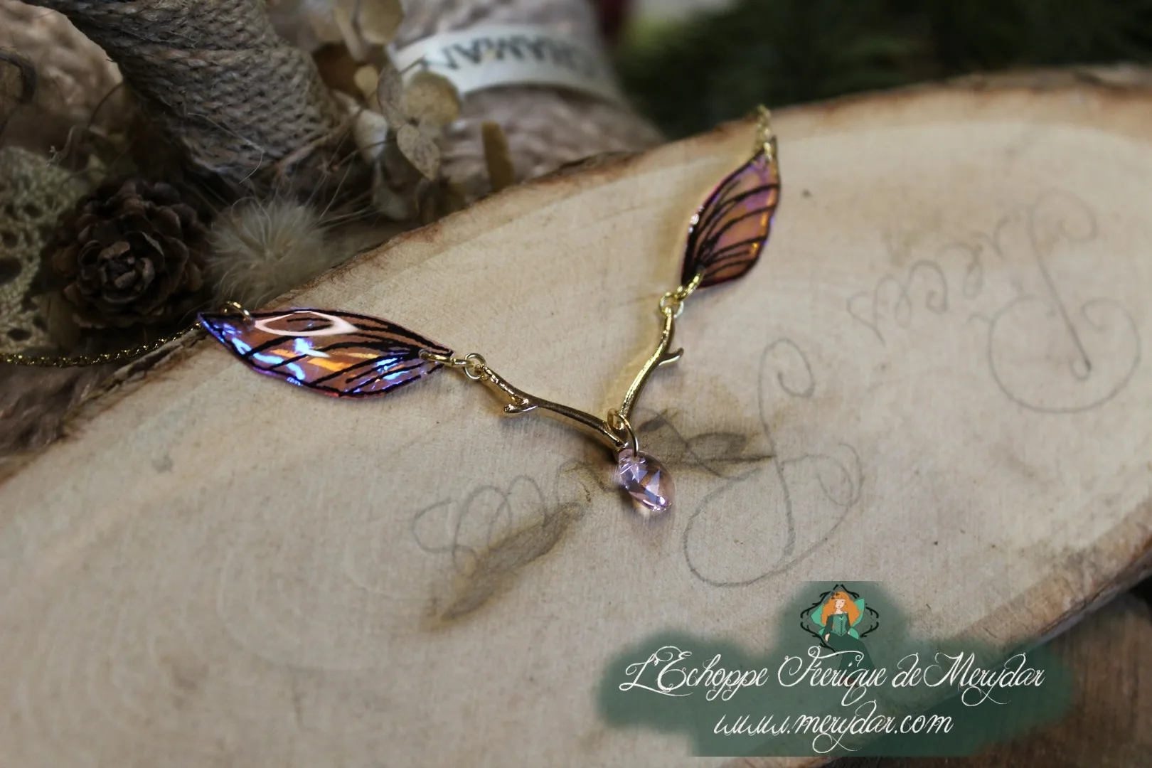 Collier pendentif branche doree avec deux ailes bleues violettes, gros plan sur bois