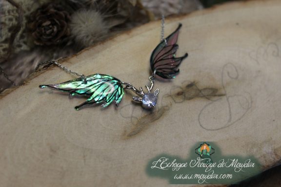 Collier pendentif deux ailes vertes avec breloque cristal, gros plan sur bois