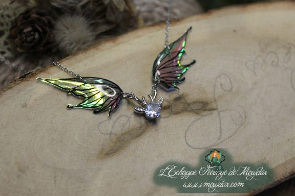 Collier pendentif deux ailes jaunes et noires avec breloque cristal, gros plan sur bois