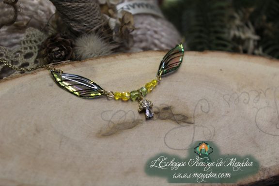 Collier pendentif branche doree avec deux ailes brunes et breloque, perles jaunes, gros plan sur bois