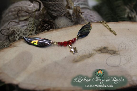 Collier pendentif branche doree avec deux ailes noires et breloque etoile, perles rouges, gros plan