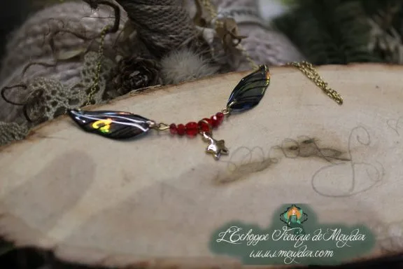Collier pendentif branche doree avec deux ailes noires et breloque etoile, perles rouges, gros plan
