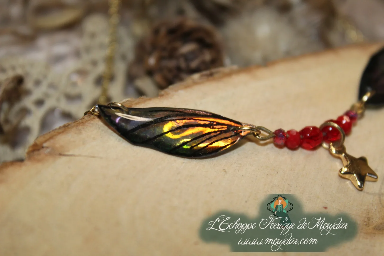 Collier pendentif branche doree avec deux ailes dorees et breloque etoile, perles rouges, gros plan