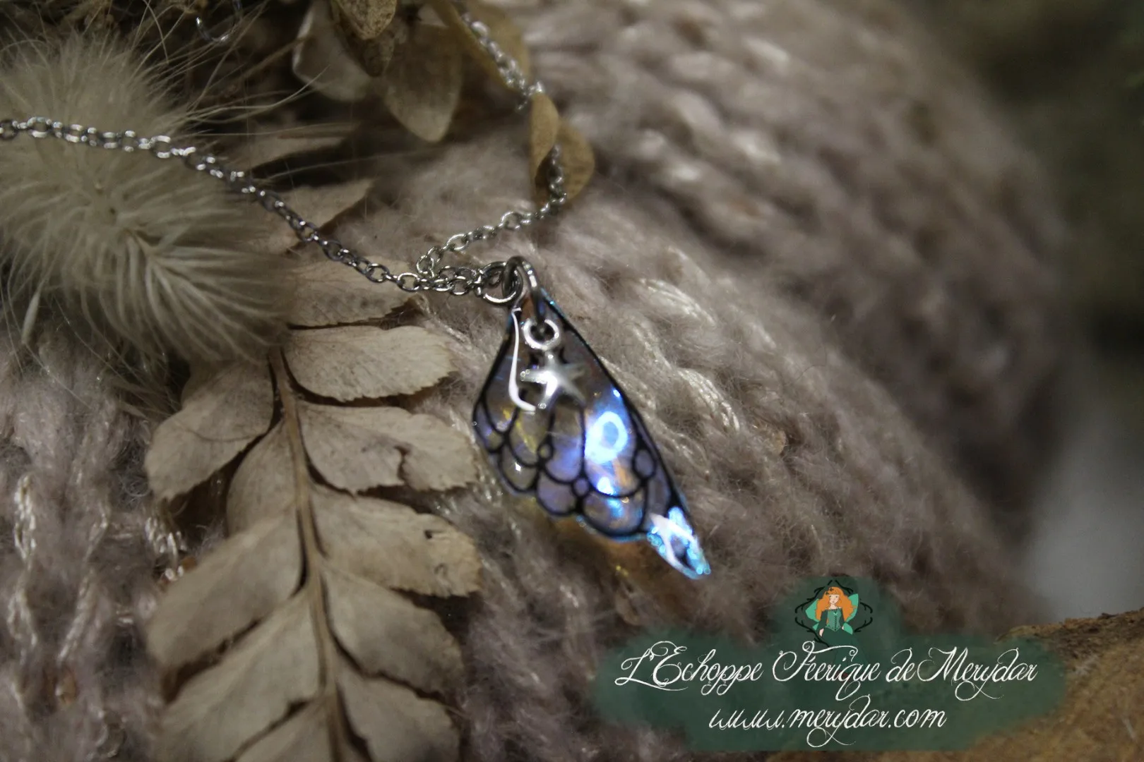 Pendentif aile texture ecailles bleue sur chaine argentee, gros plan sur fougere