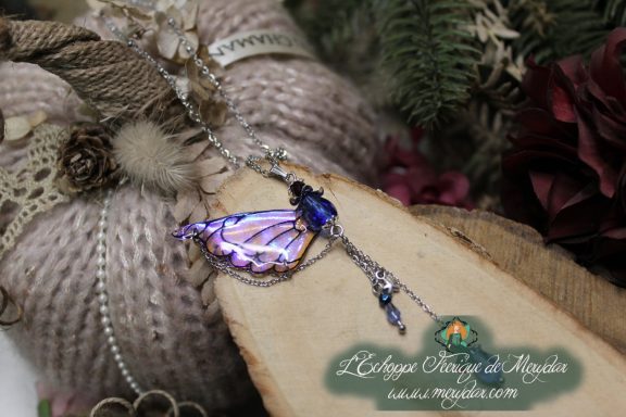 Pendentif aile violette avec chaine et perles pendantes, gros plan sur bois