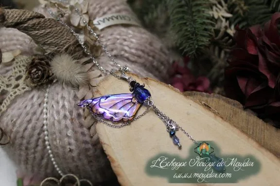 Pendentif aile violette avec chaine et perles pendantes, gros plan sur bois