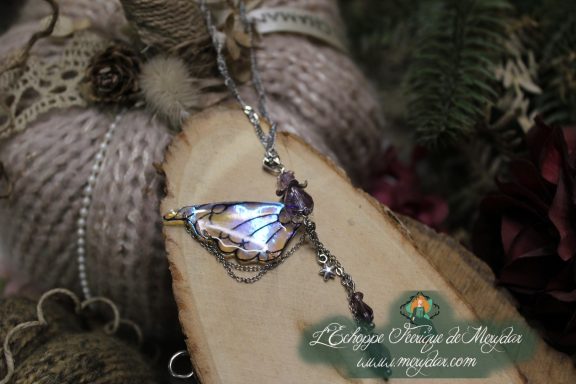 Pendentif aile violette avec breloque filigrane sombre, vue rapprochee sur bois