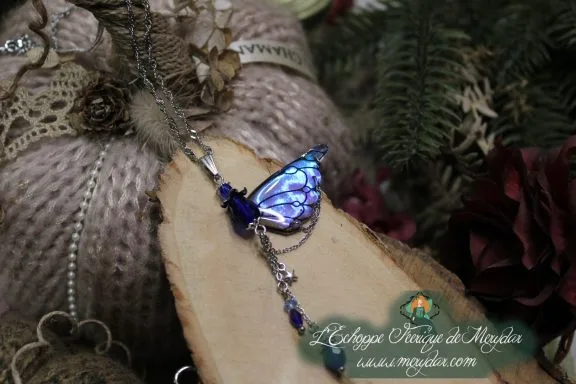 Collier pendentif papillon bleu avec perle bleue pendante, gros plan sur bois