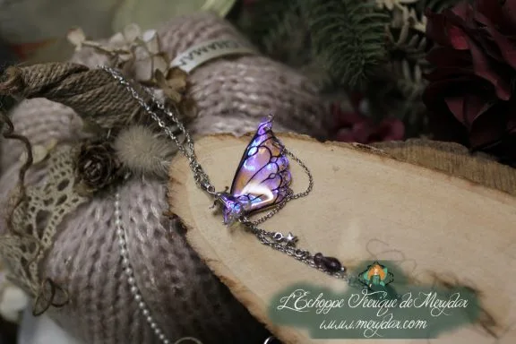 Pendentif papillon violet avec chainettes pendantes, gros plan sur bois