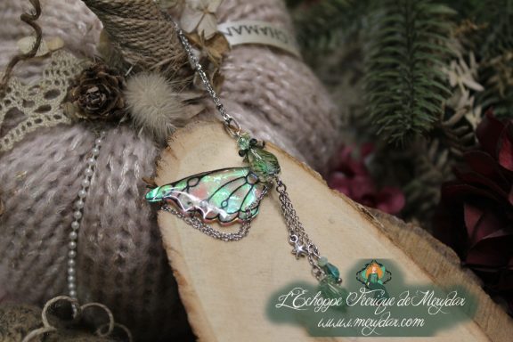 Pendentif papillon turquoise avec chainettes pendantes, gros plan sur bois